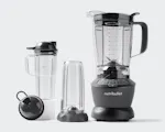 Product preview 5 of 8. Thumbnail nutribullet with cup, handled cup and lids on grey background.
